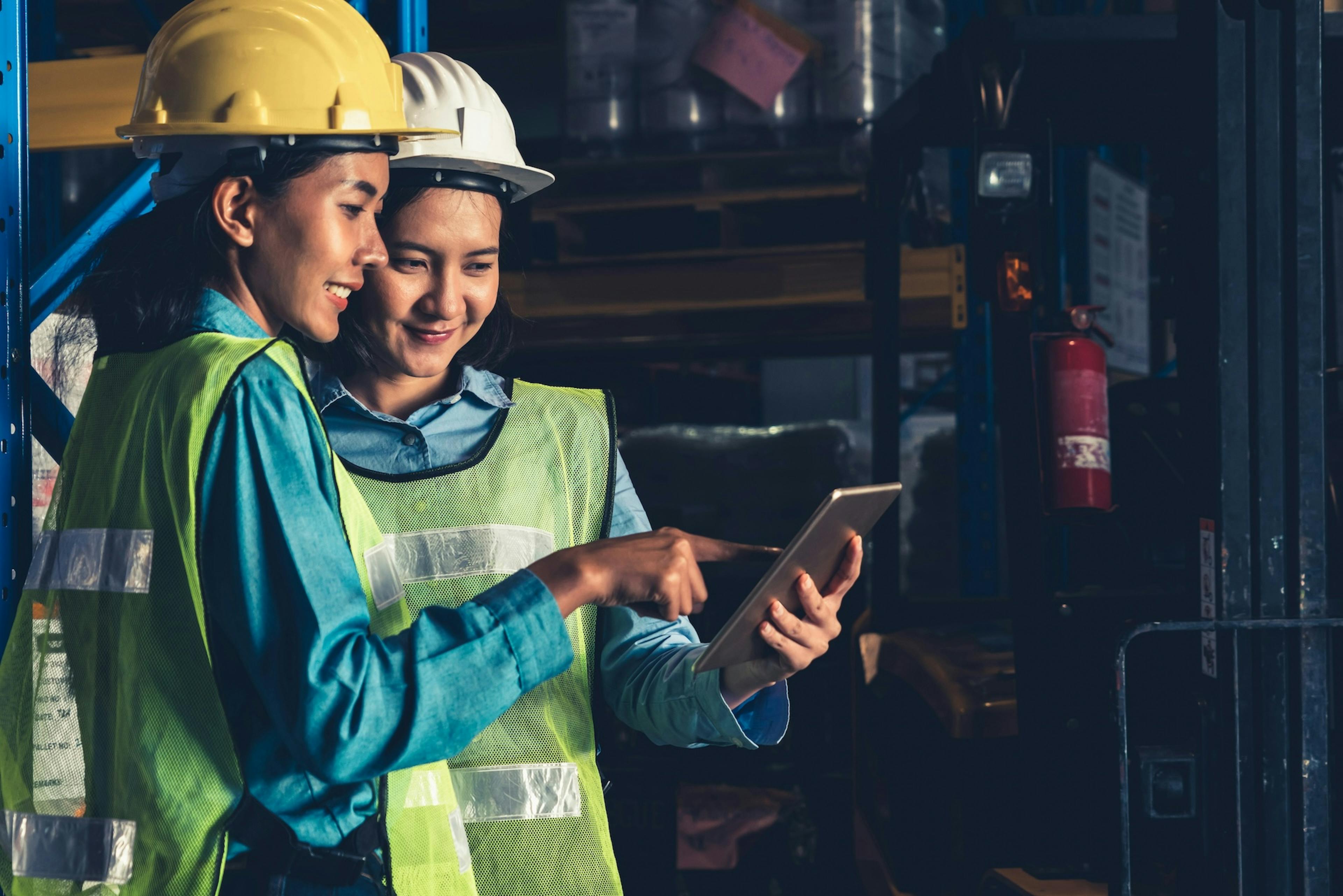 Two workers smiling while looking at the tablet 