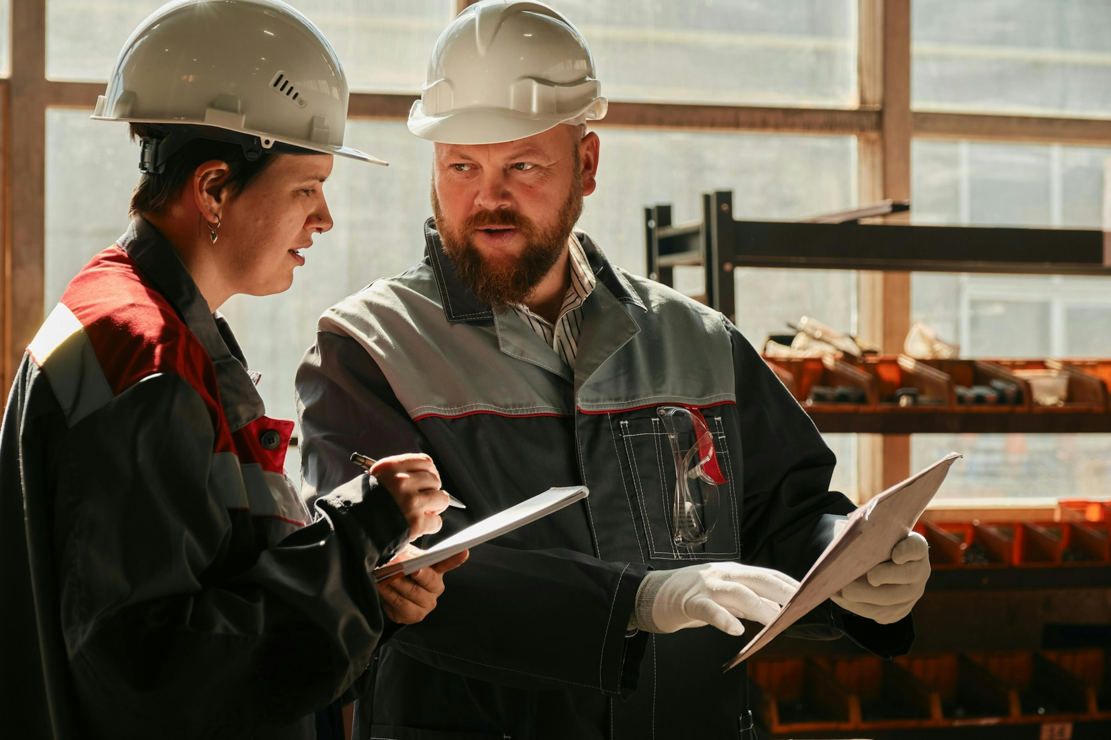 two workers with white helmets holding notebooks