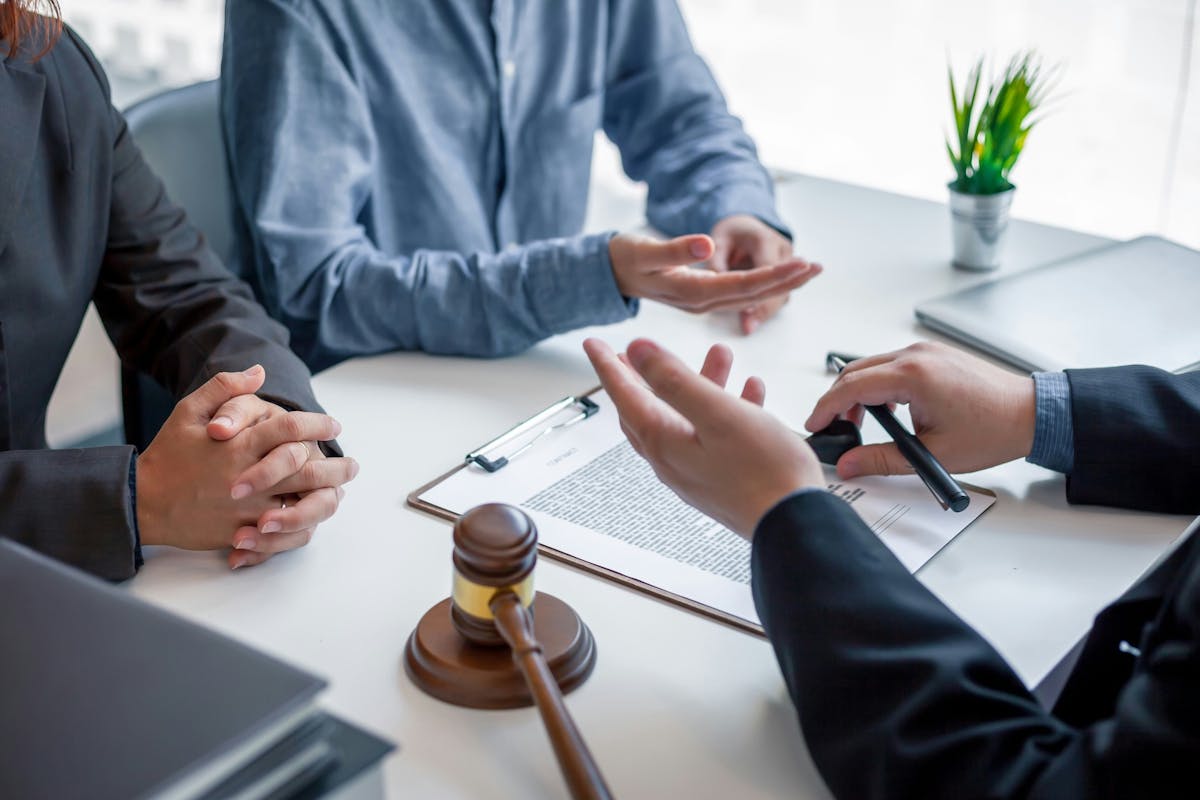 Three people debating over legal documents sitting at the table