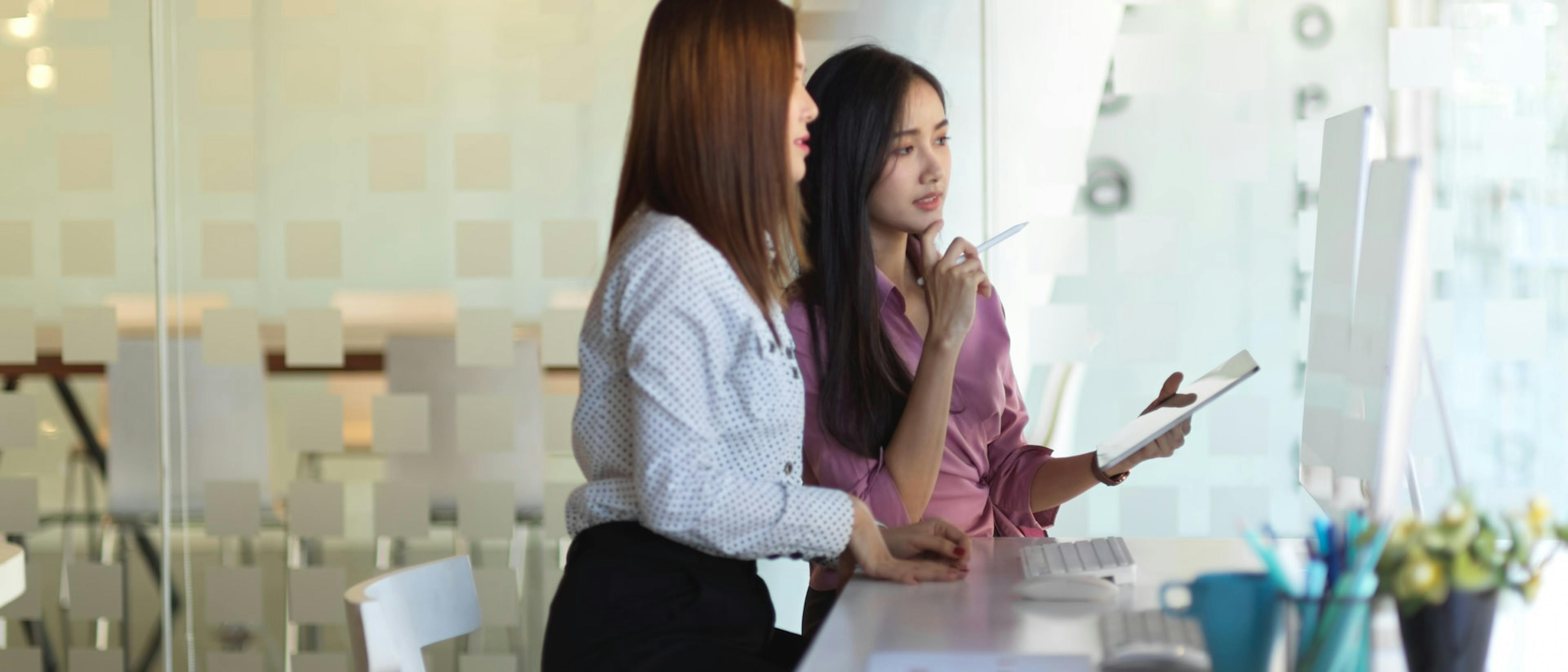 2 female employees looking at computer screens at counter