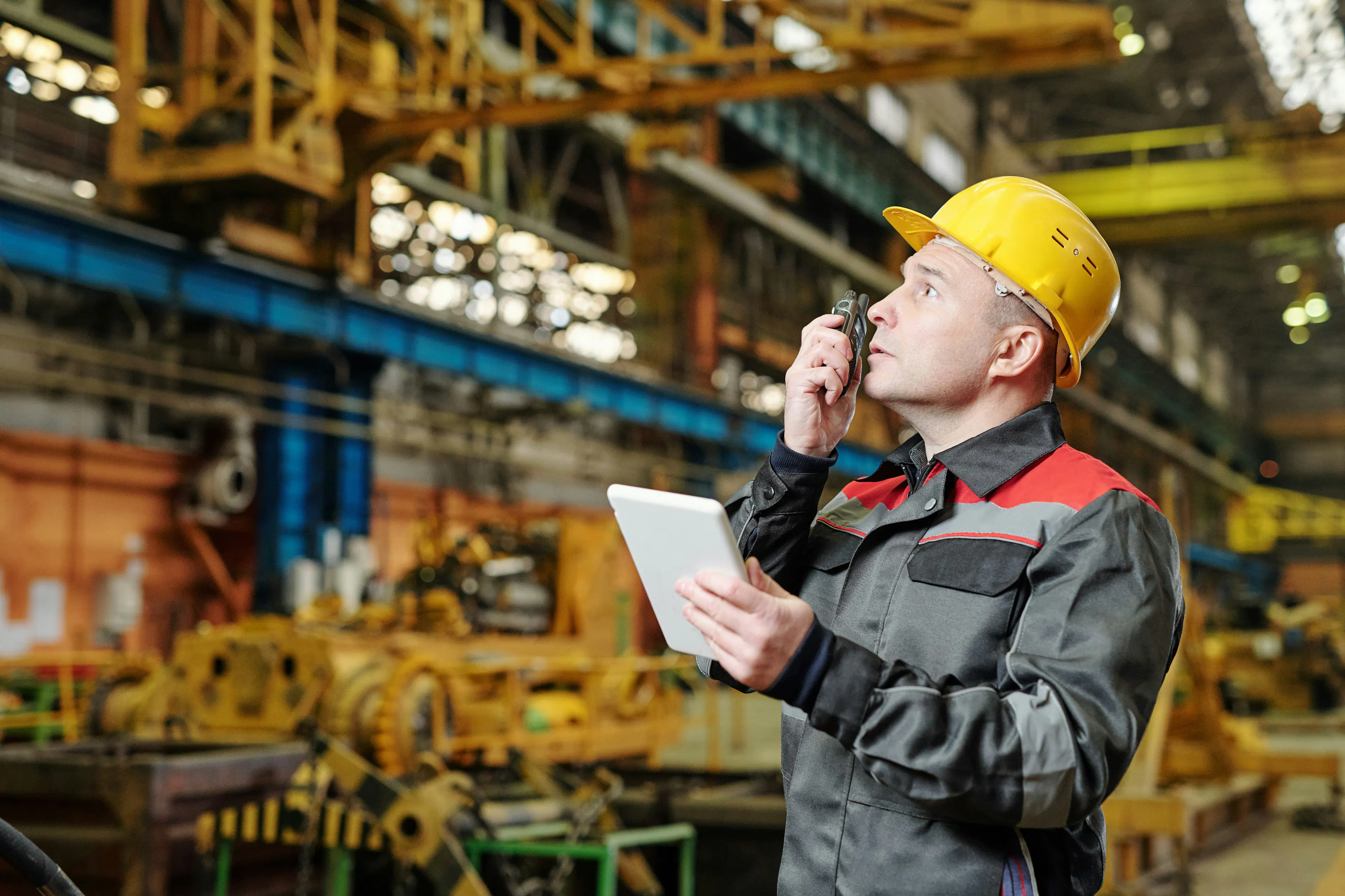 Industrial worker using radio and tablet on factory floor