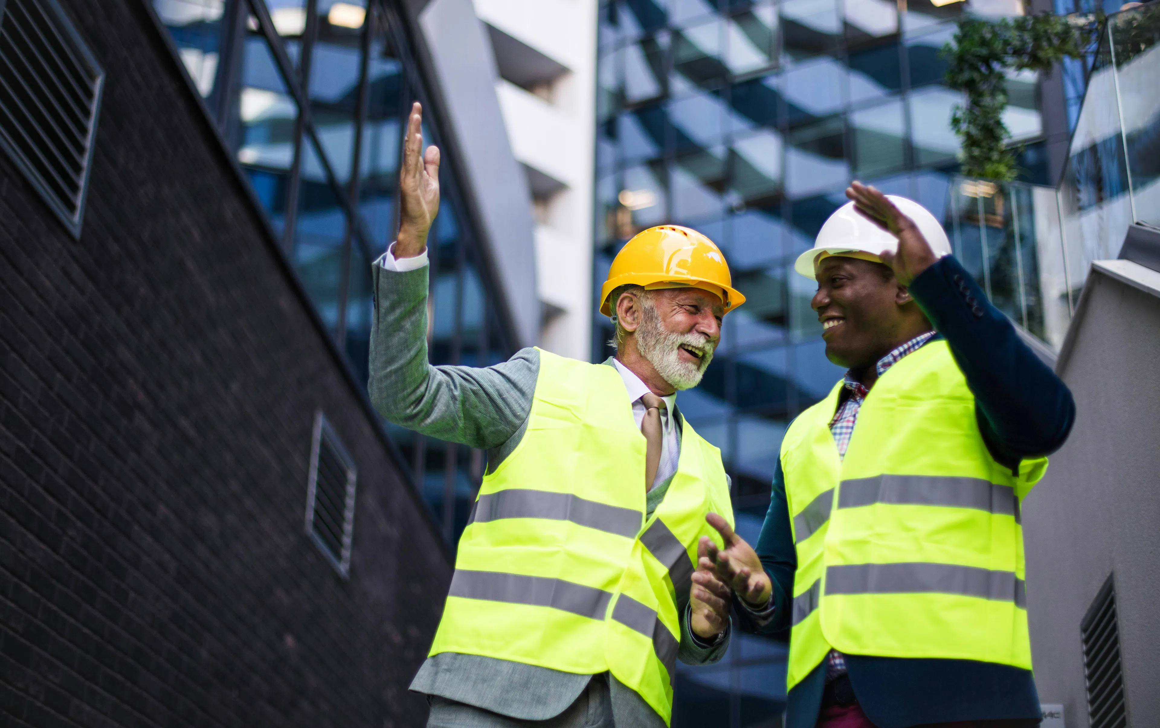 Two frontline workers celebrating outdoors in safety vests