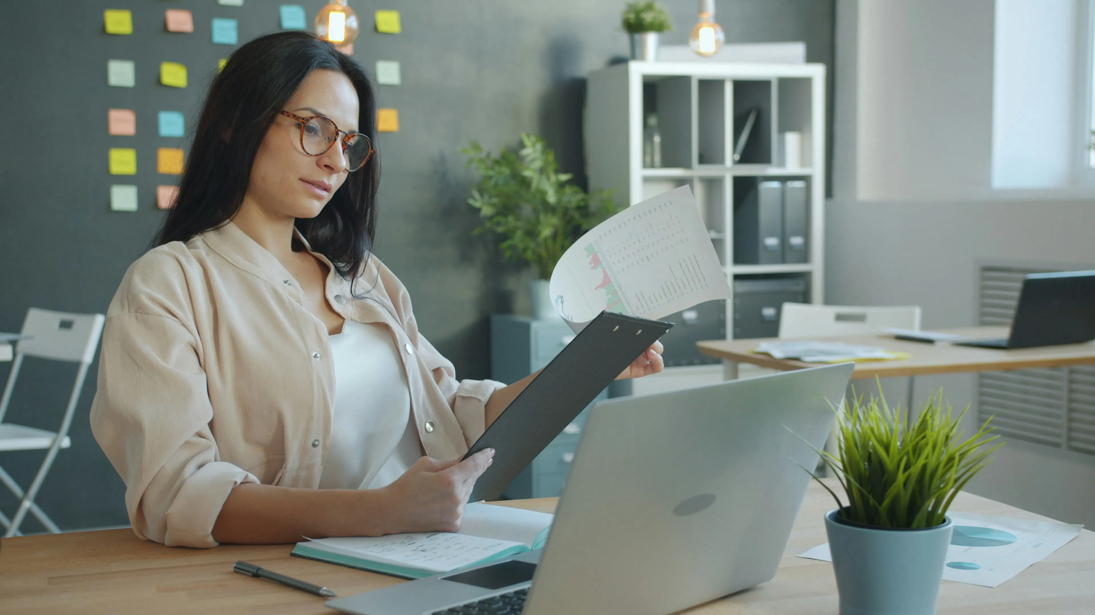 HR professional holding data chart clipboard at office desk