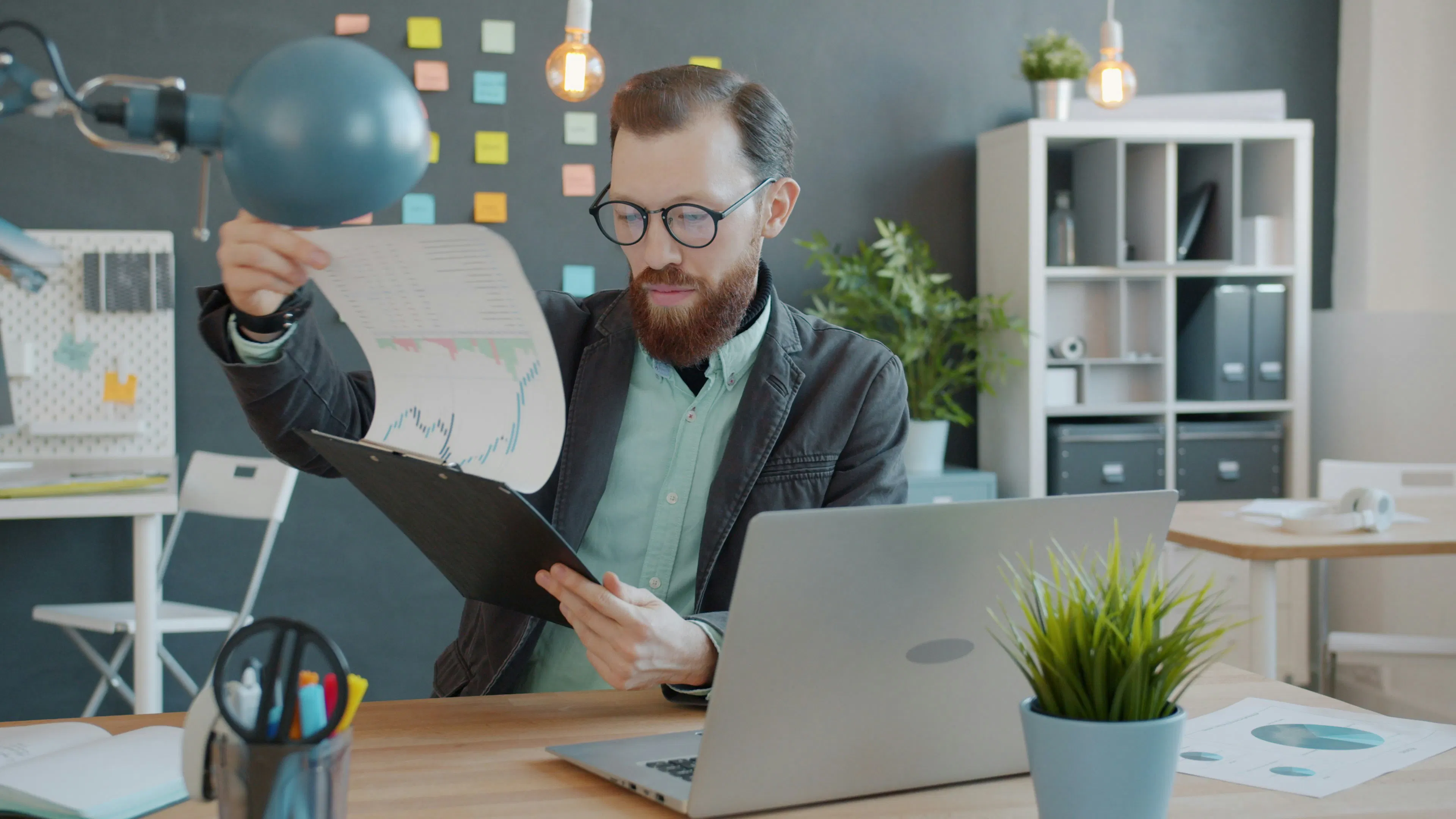 Man reviewing document on clipboard at office desk