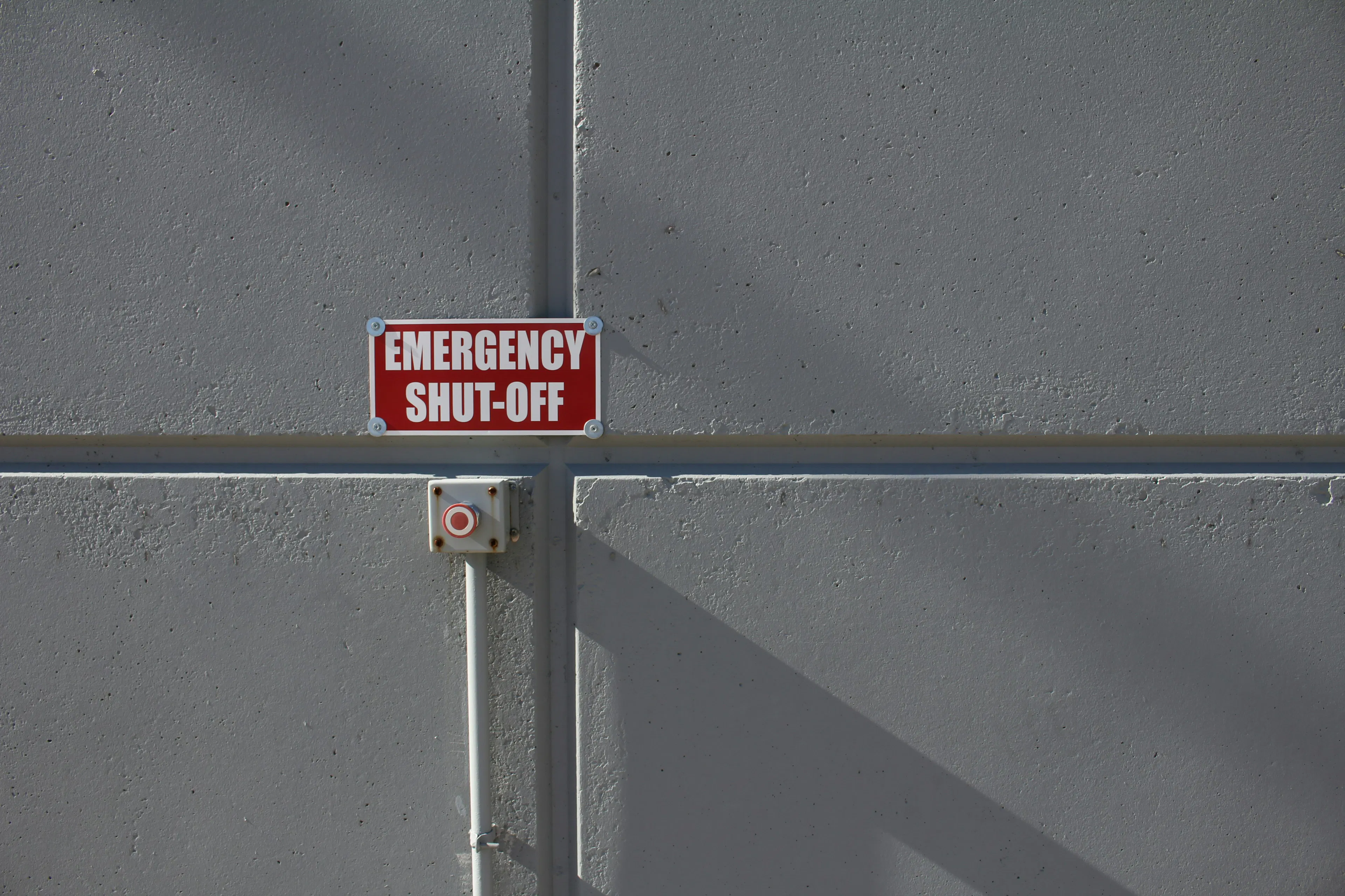 Red emergency shut-off sign on concrete wall