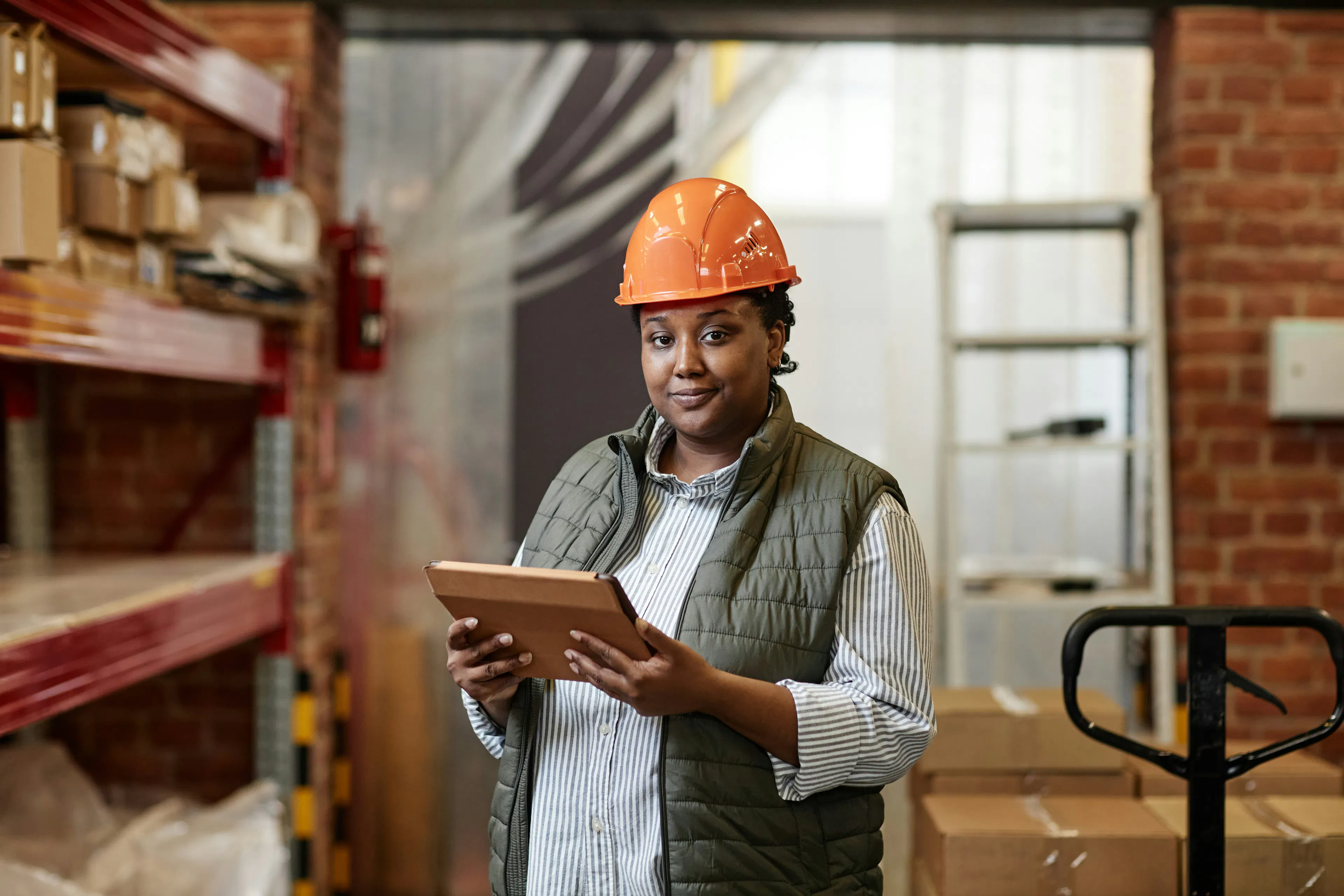 Operations manager in hard hat reviewing tablet in warehouse