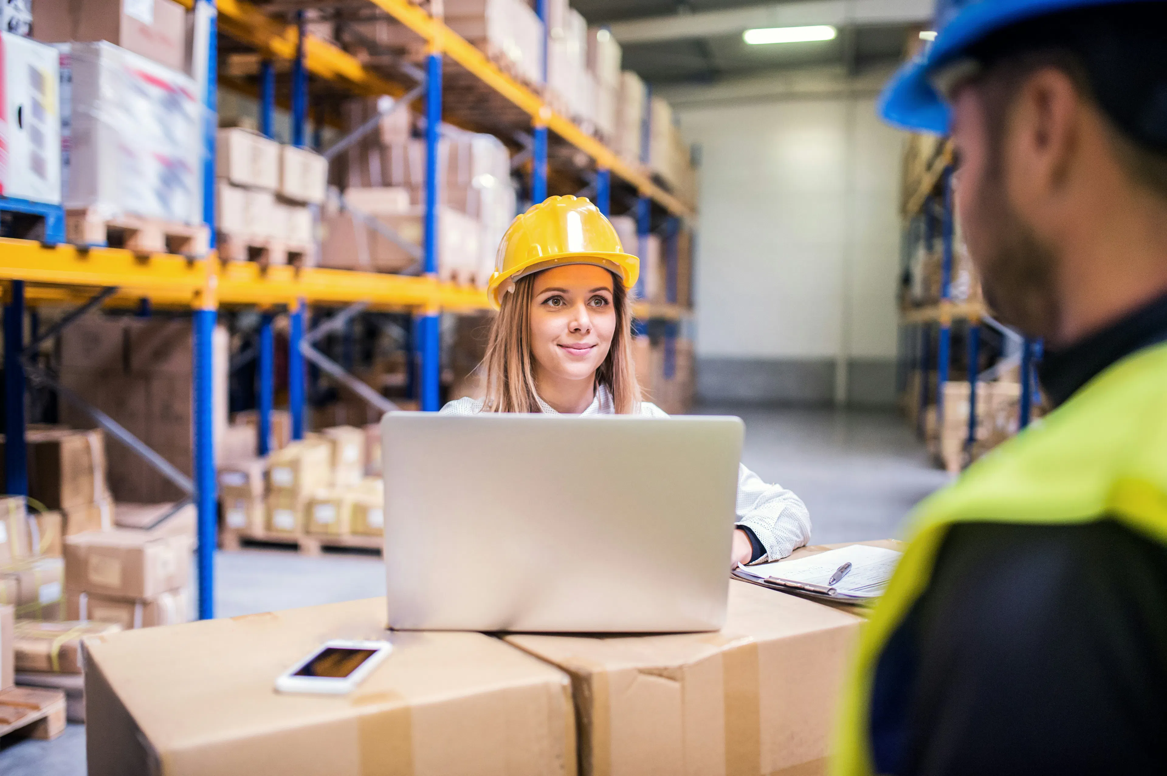 Warehouse manager and worker reviewing laptop in distribution center