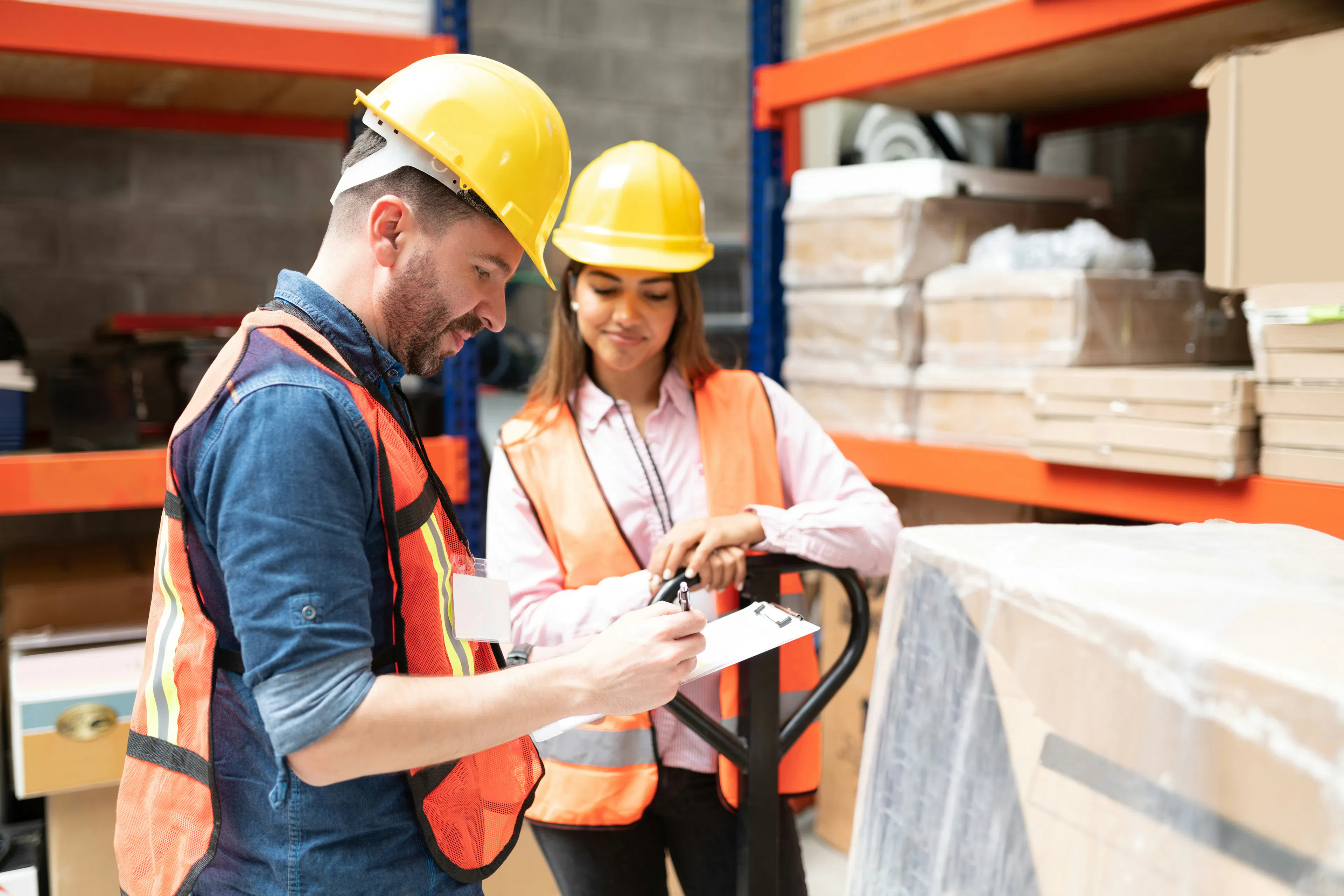  Two warehouse workers reviewing notes on clipboard