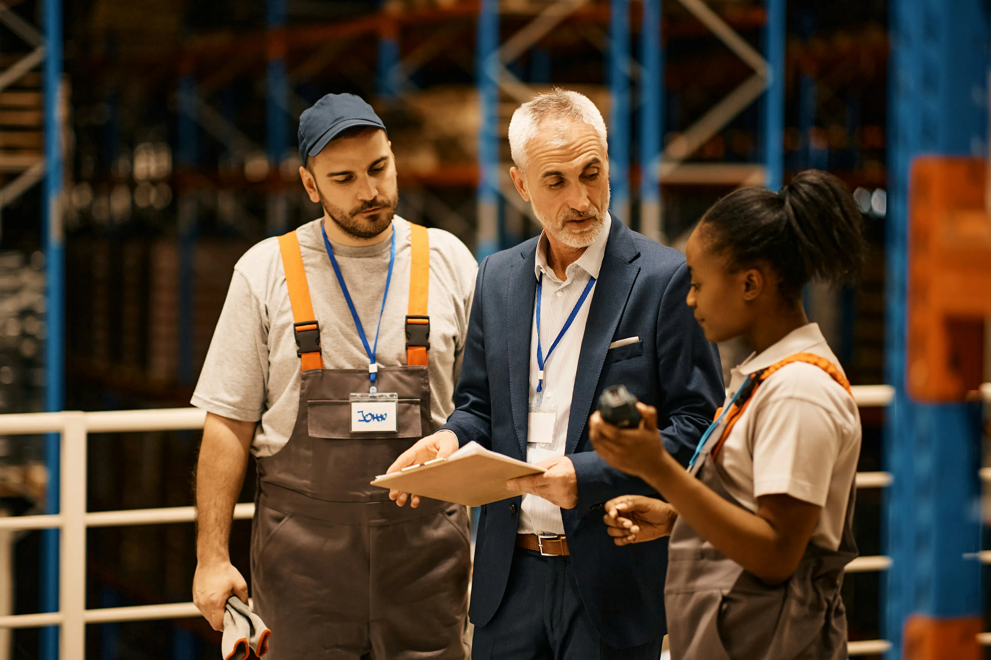 HR leader reviewing document with two frontline workers in warehouse