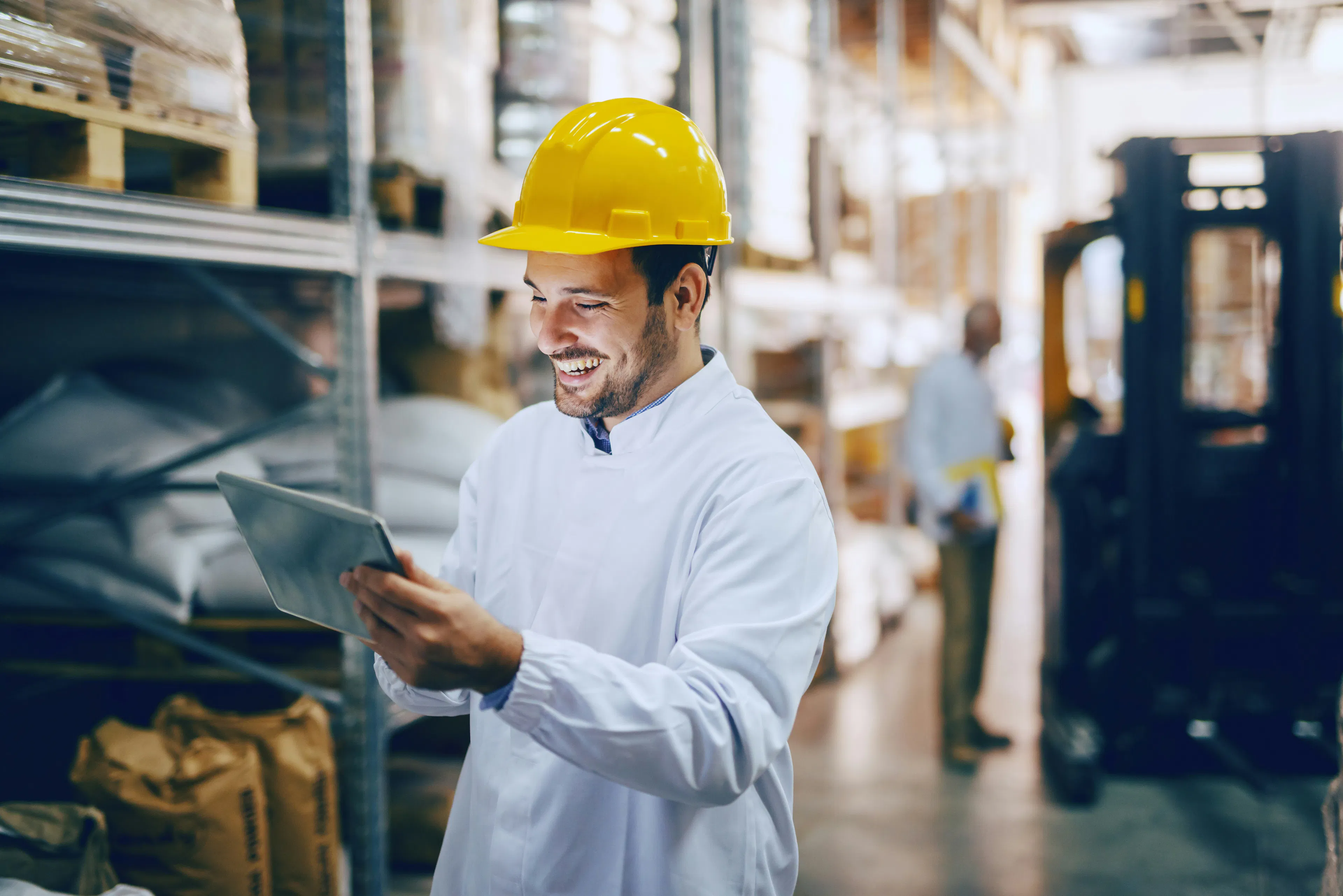 Smiling warehouse worker reviewing data on tablet