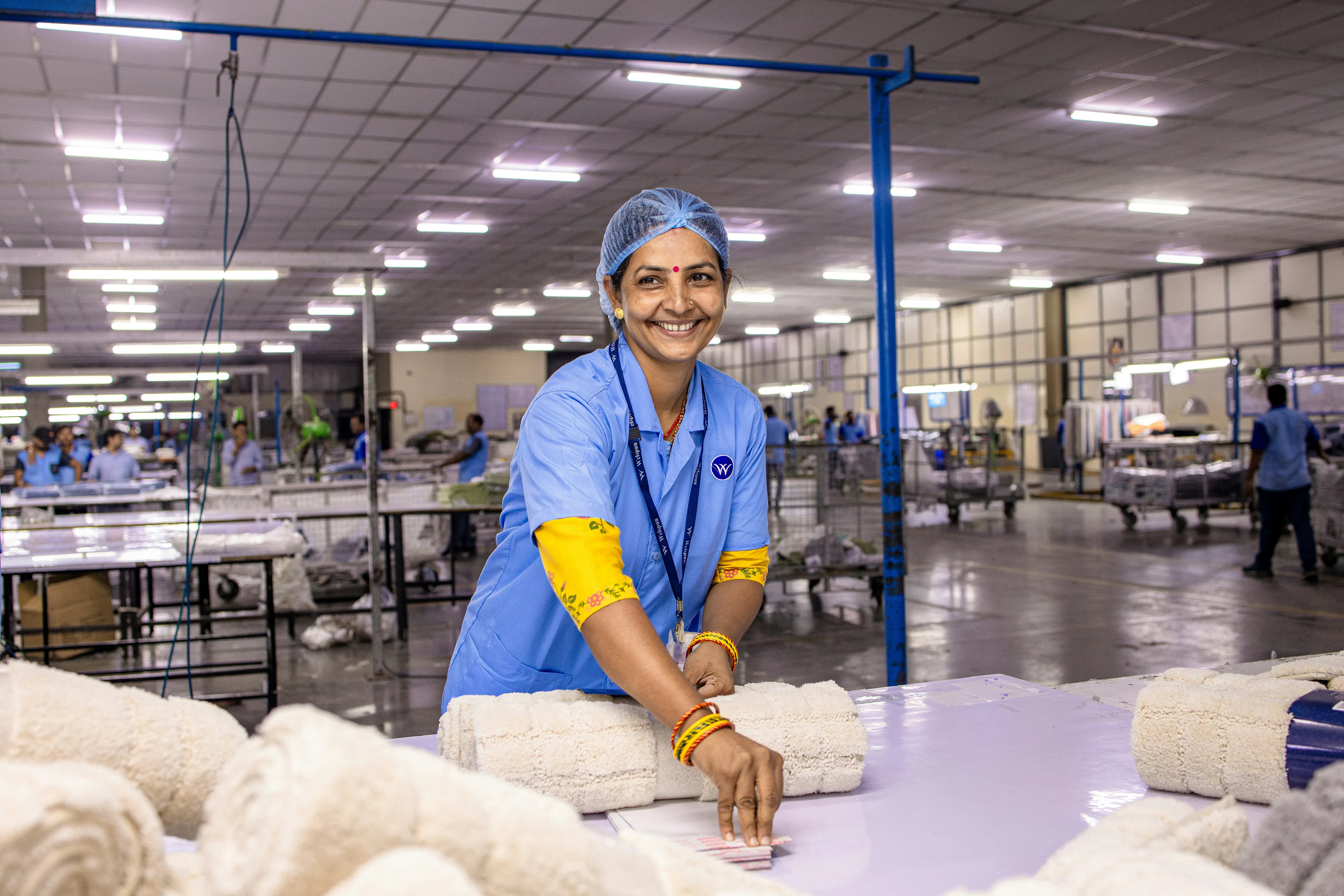 Smiling textile factory worker in a blue uniform and hairnet