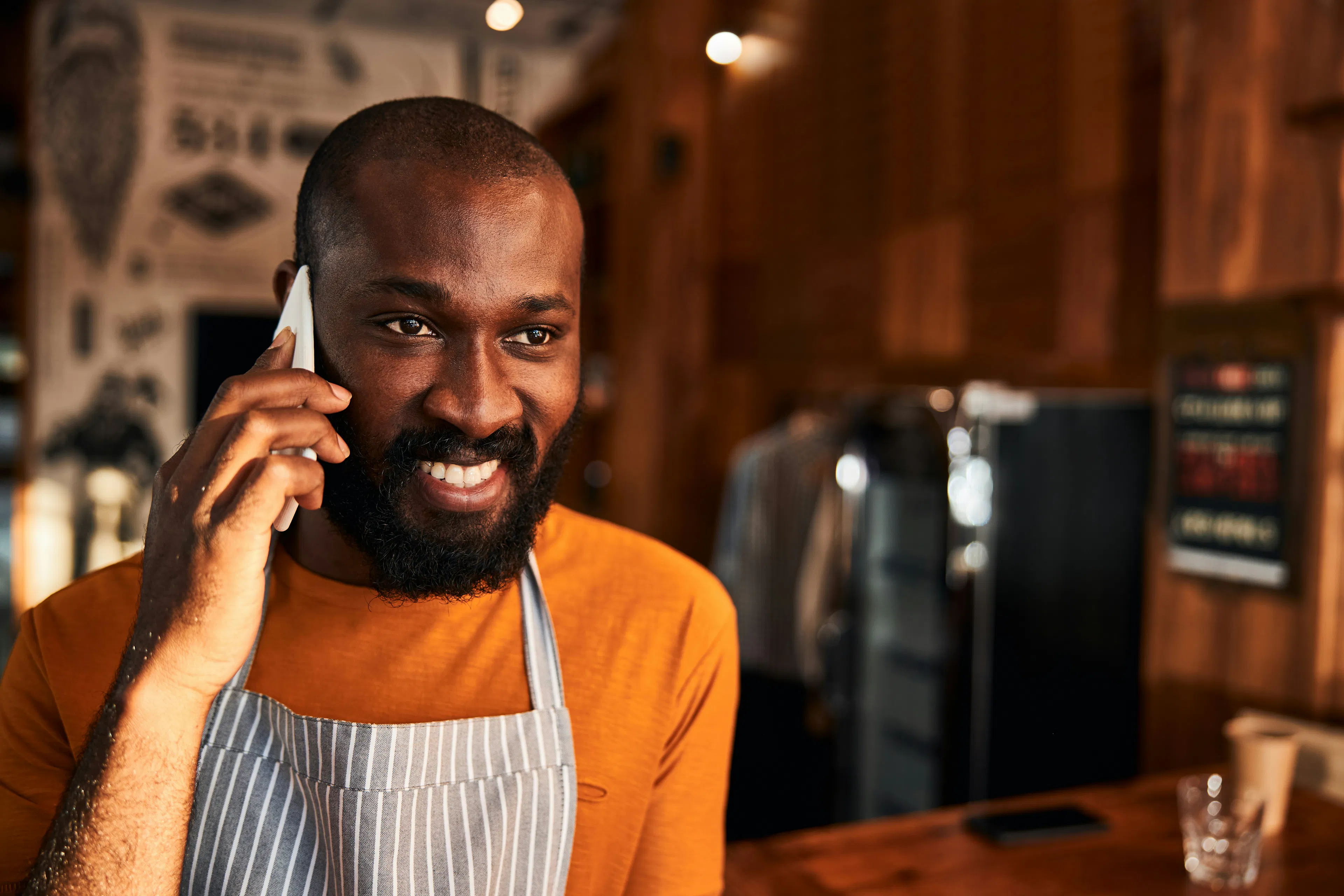 Smiling worker in an apron talking on a phone
