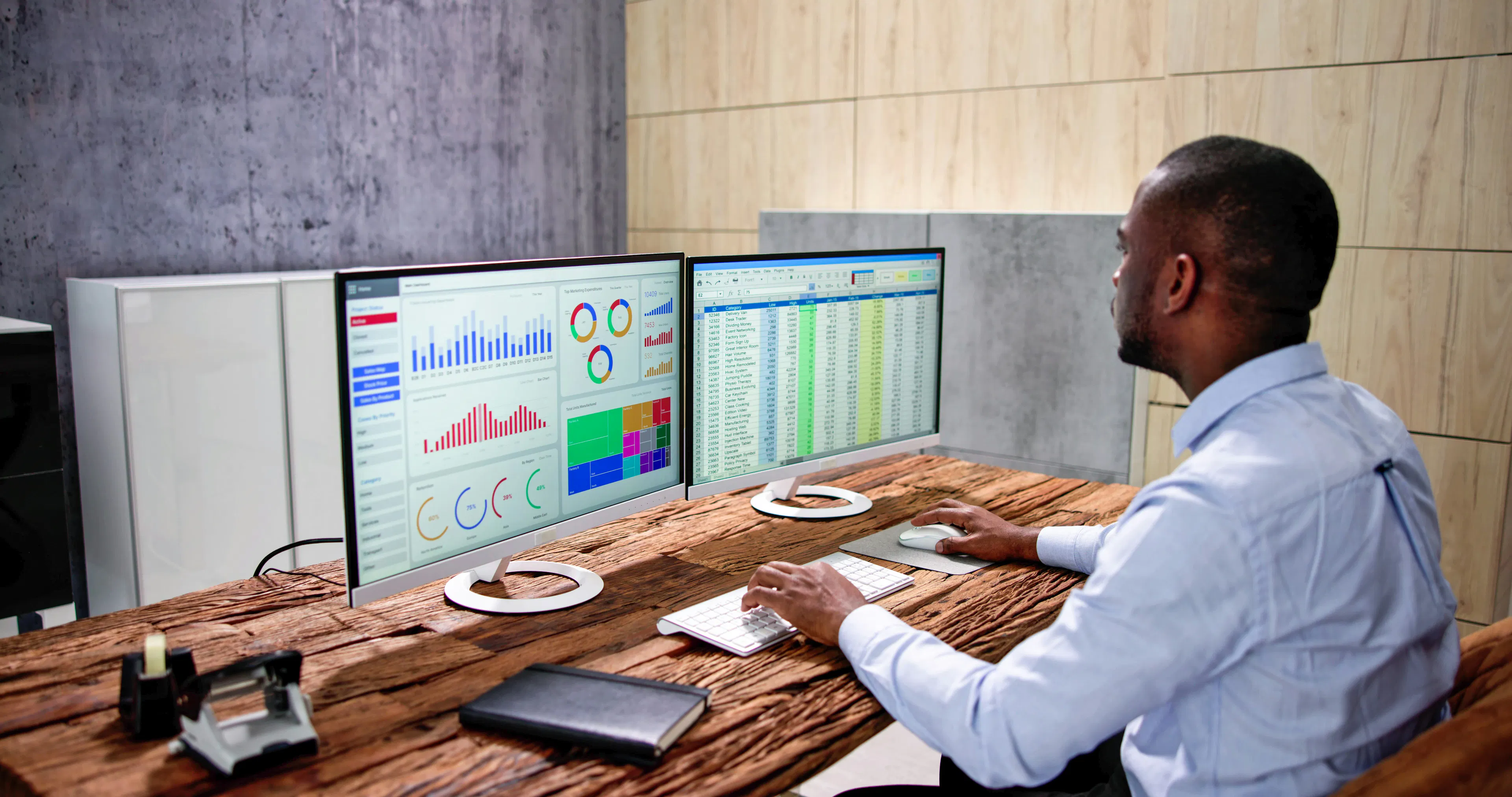 Analyst reviewing workforce dashboard and spreadsheet on dual monitors