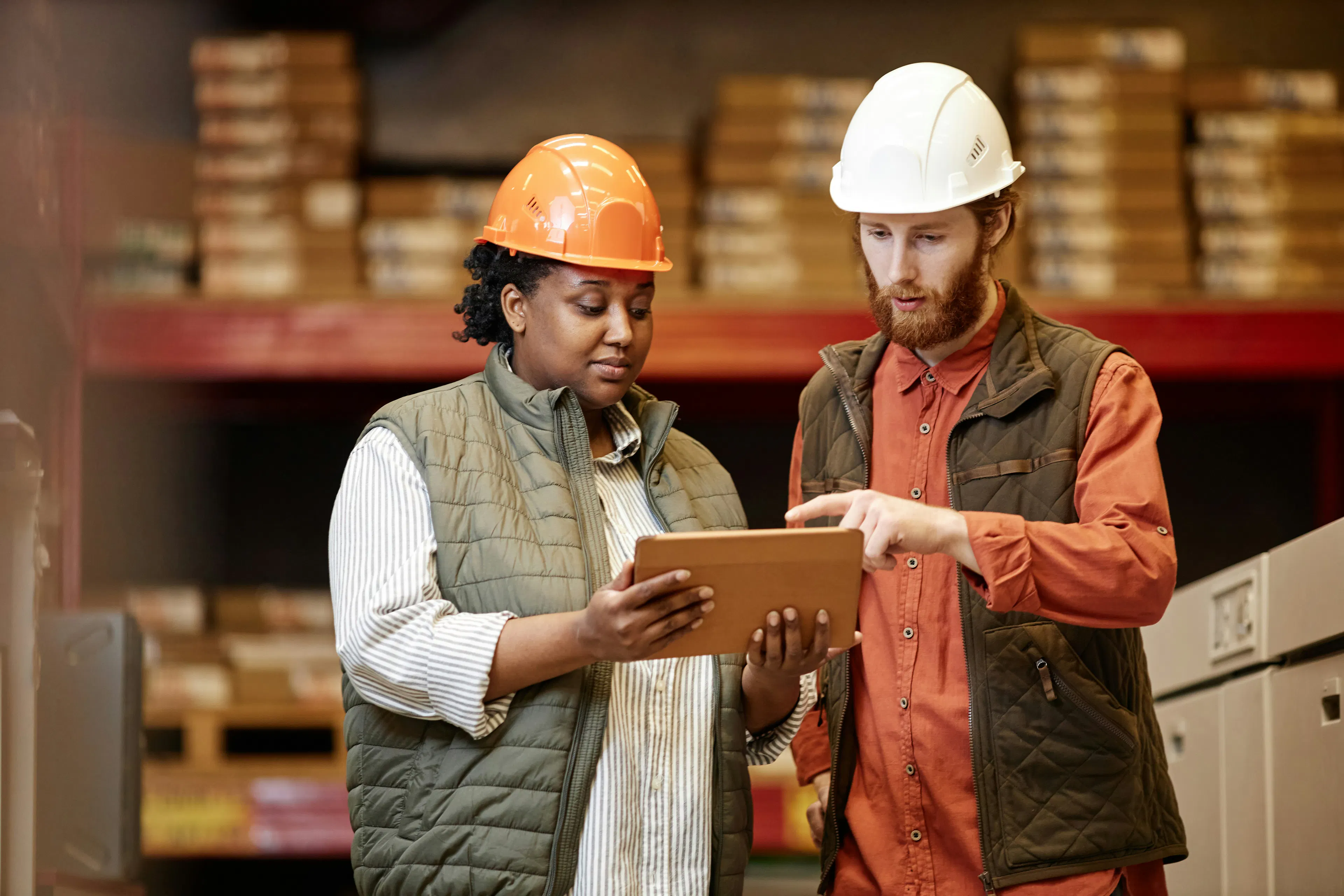 Two warehouse workers reviewing data on tablet