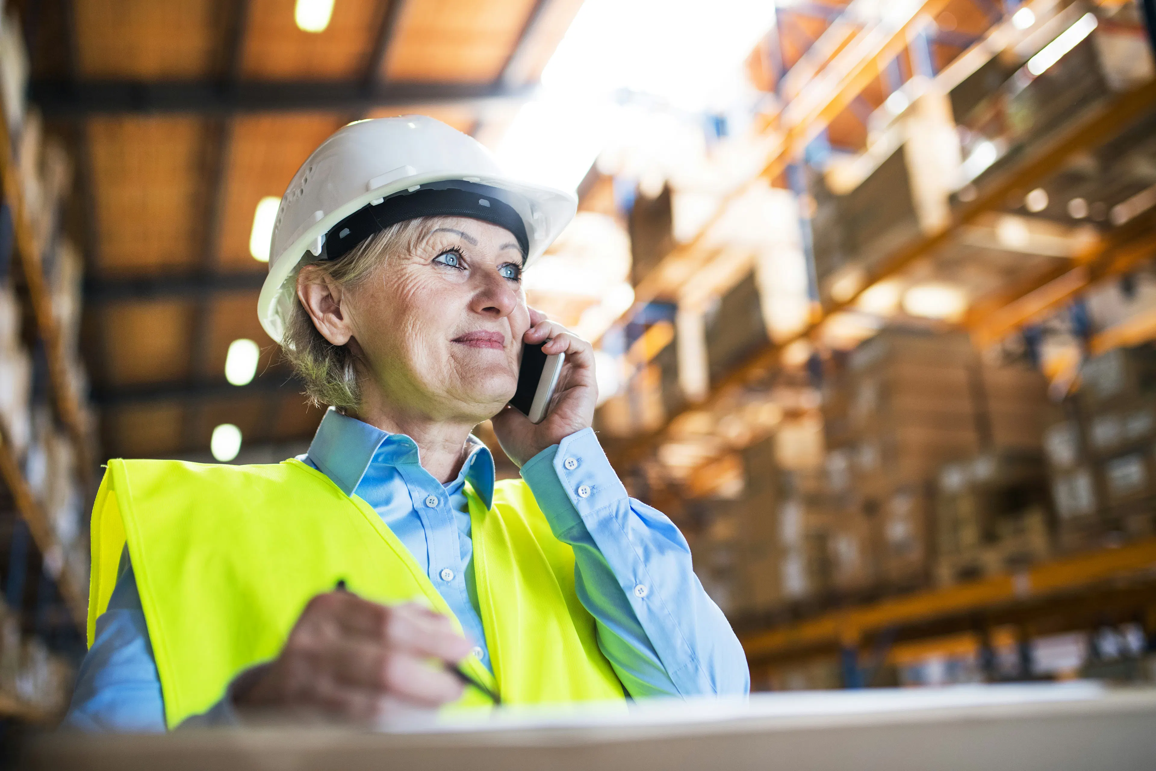 Warehouse worker in hard hat talking on phone