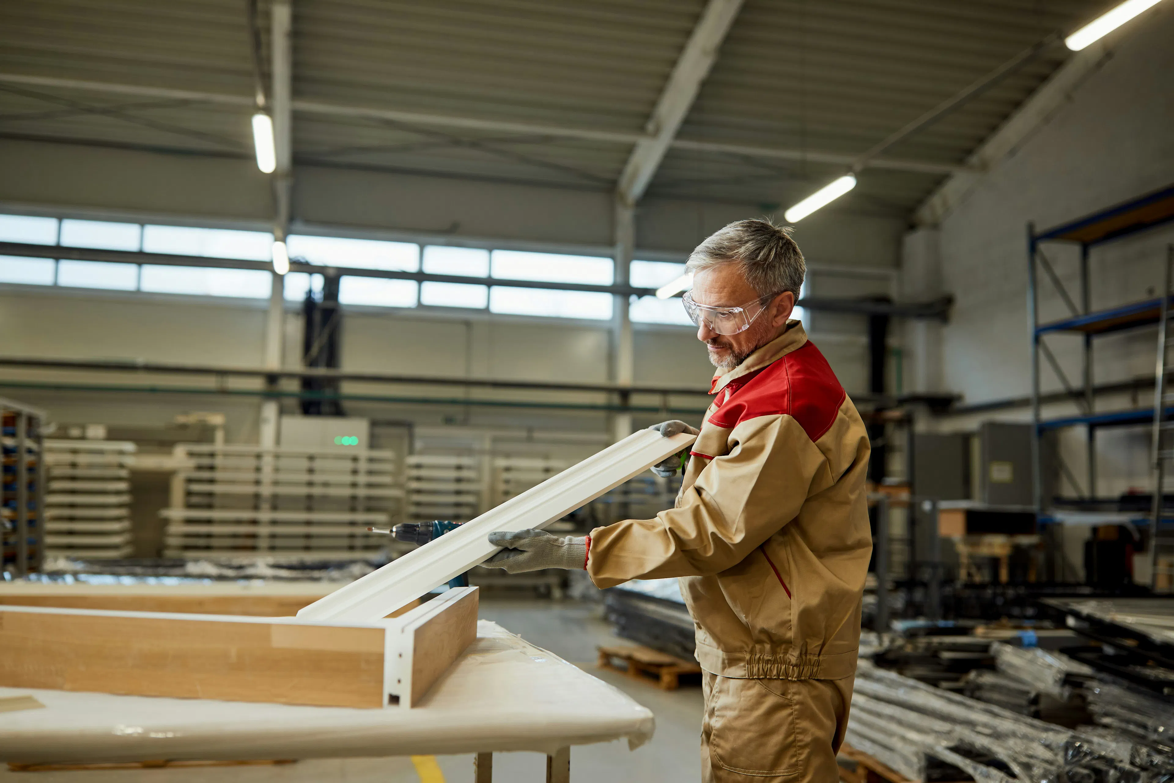 Worker assembling a window frame in a manufacturing facility.
