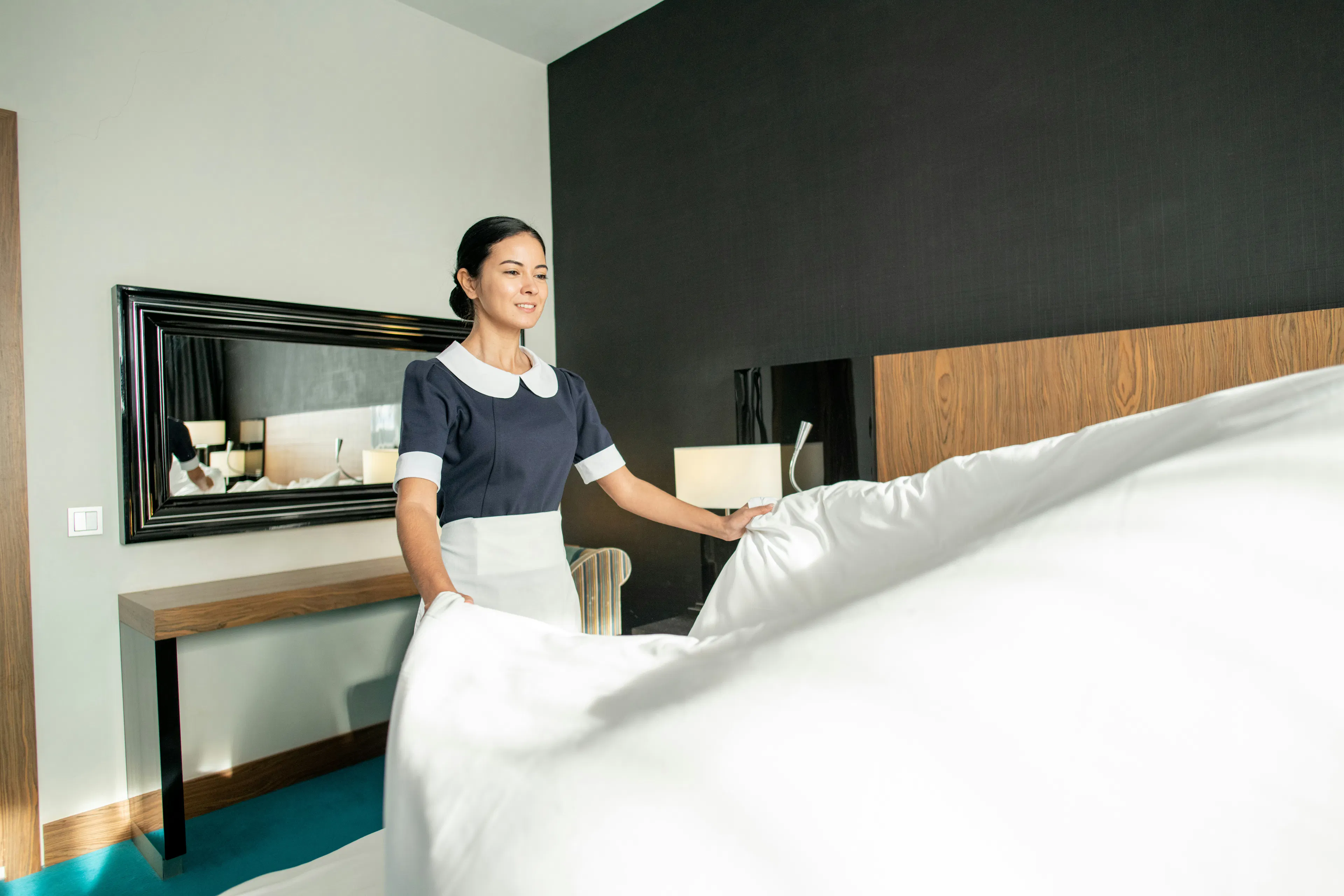 Housekeeper smoothing linen on a bed in a hotel room