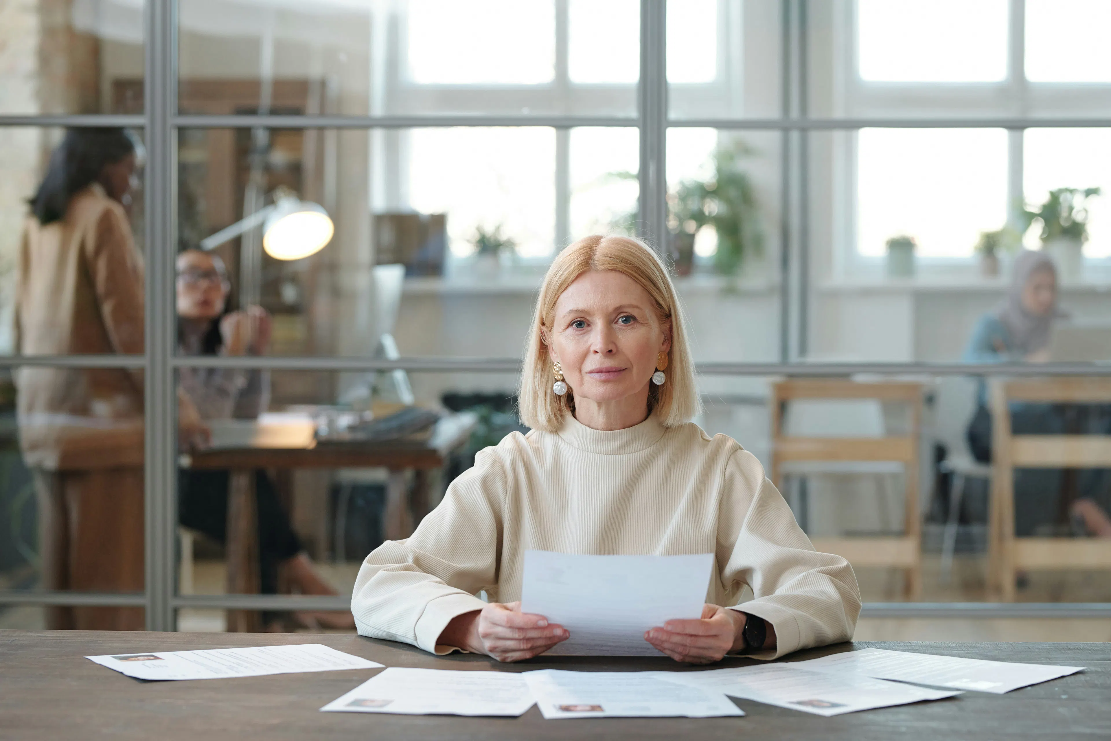 Woman at desk holding a document with papers spread out