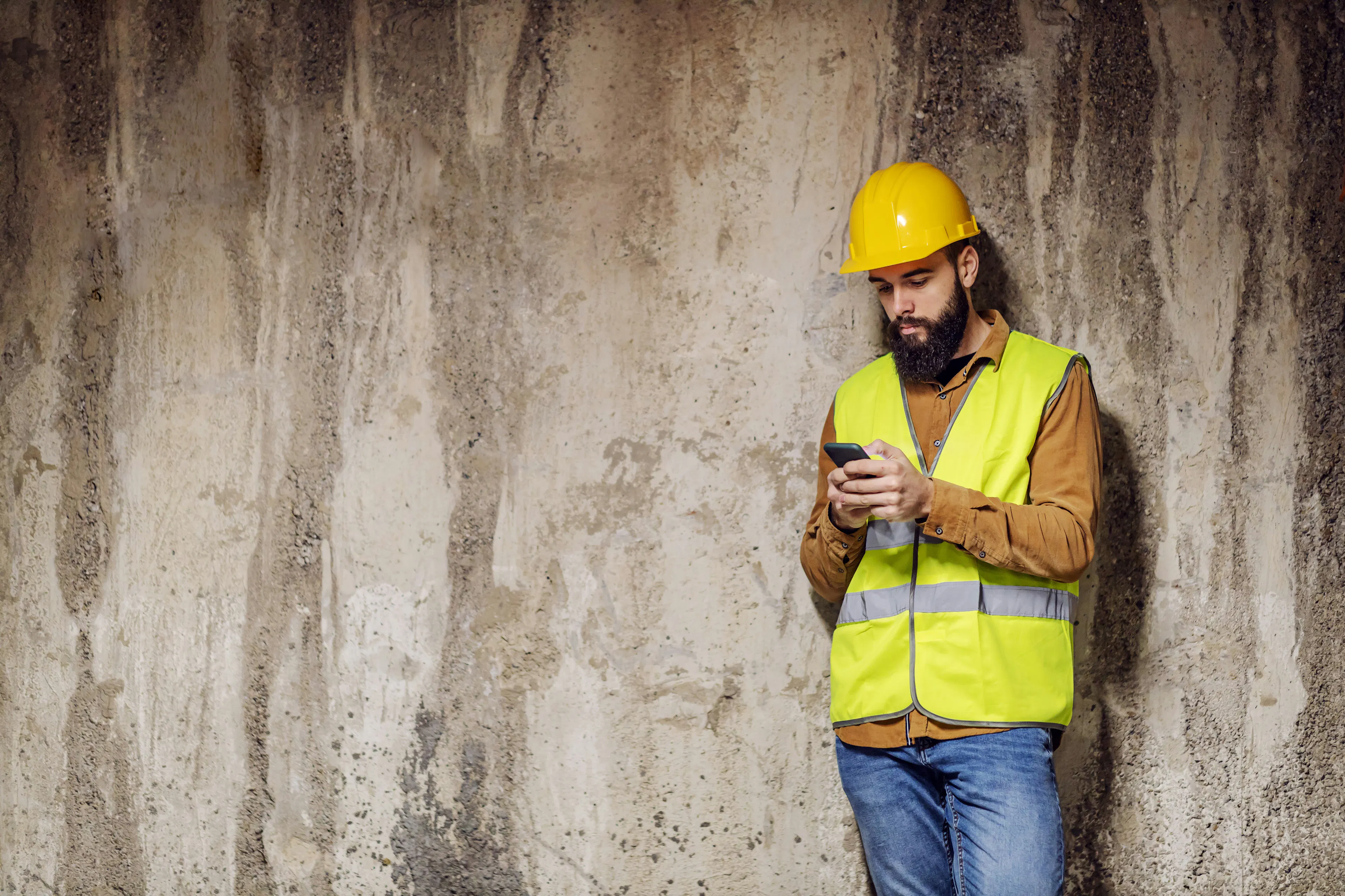 Construction worker in a hard hat looking at a smartphone.