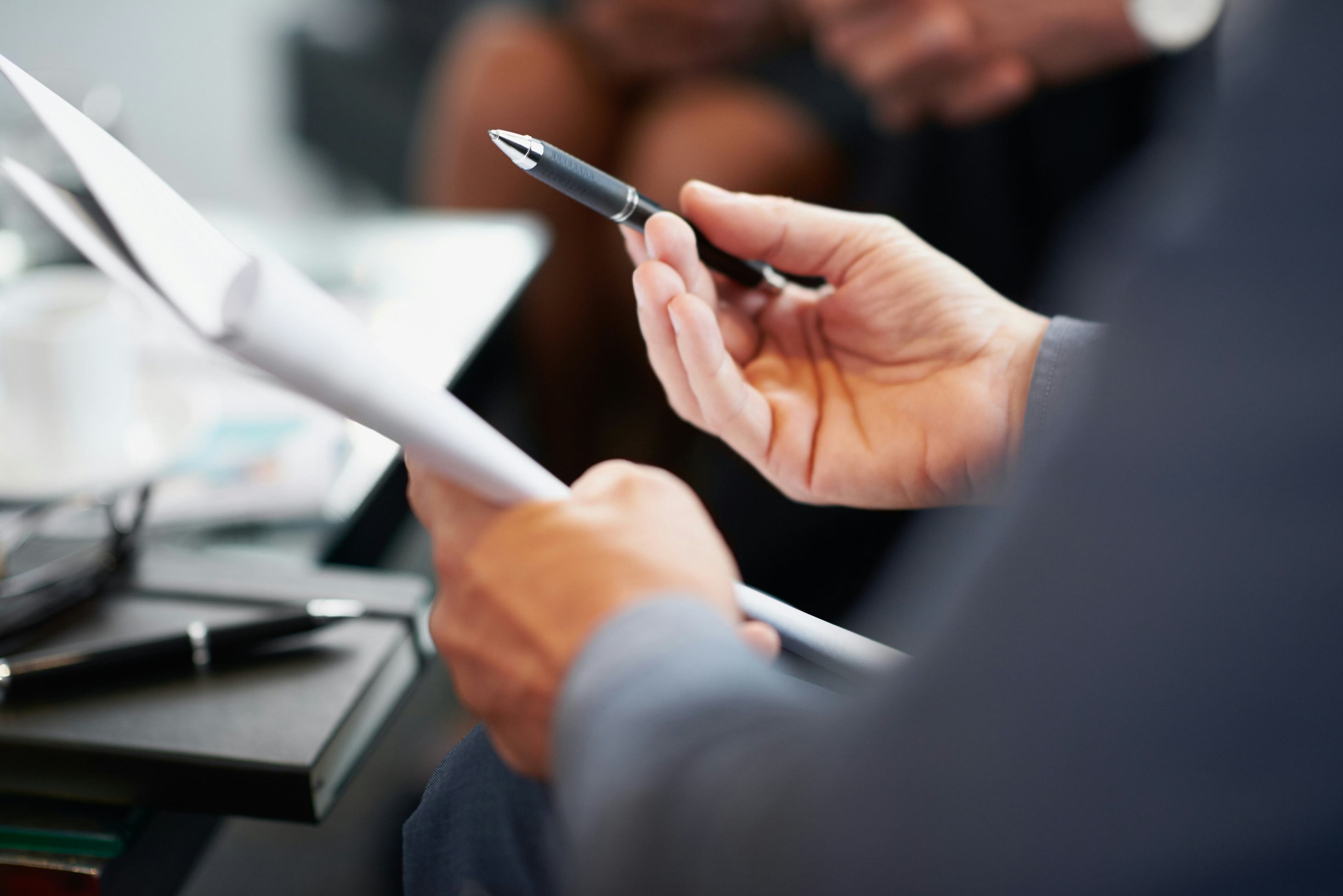 Person in meeting holding paper document and pen