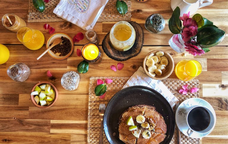 A colorful and healthy brunch is served at a Portugal yoga retreat, featuring pancakes with fruit, coffee, and more.