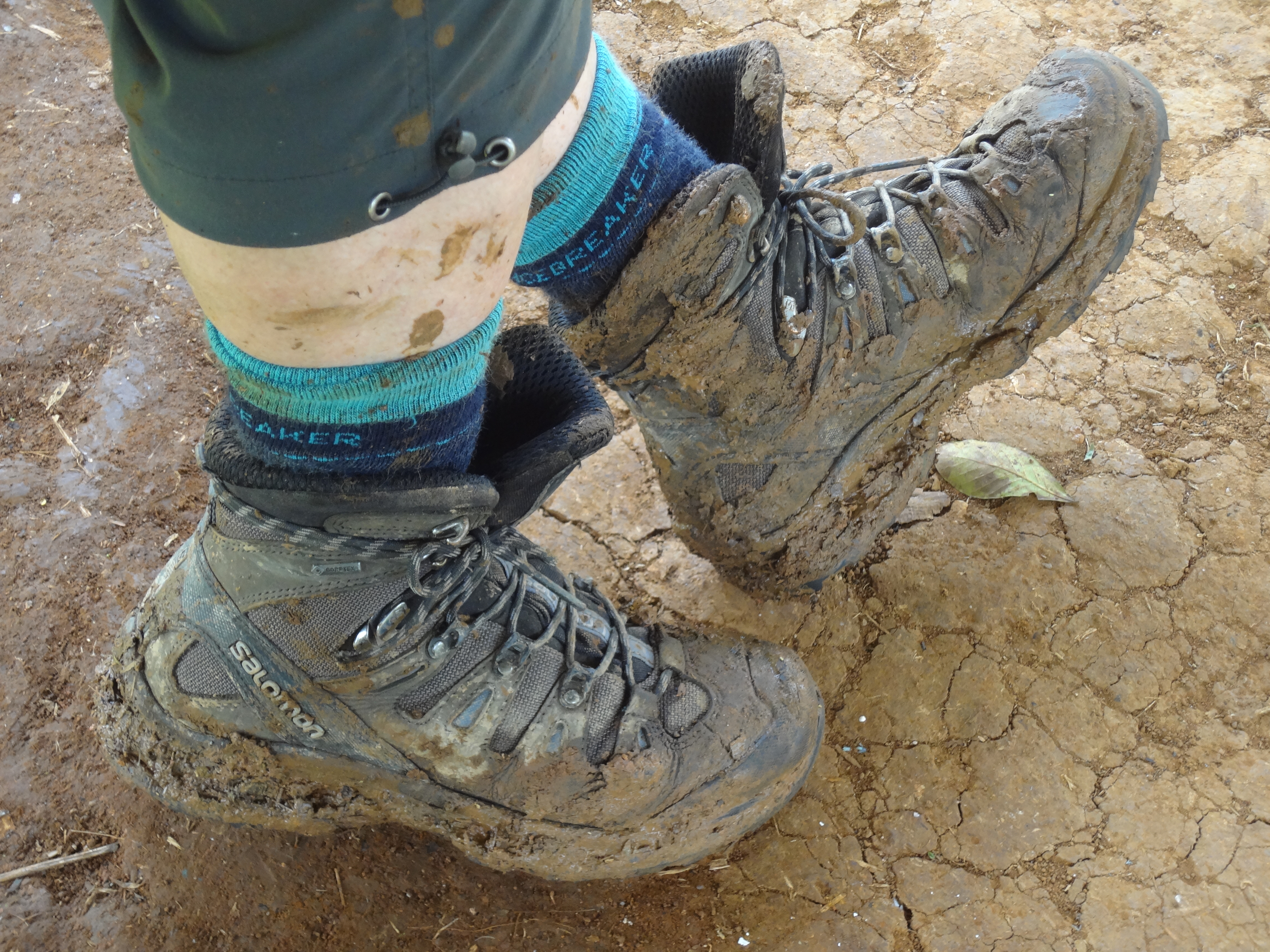 A hiker's boots are muddy while walking along the Kokoda Track in Papua New Guinea.