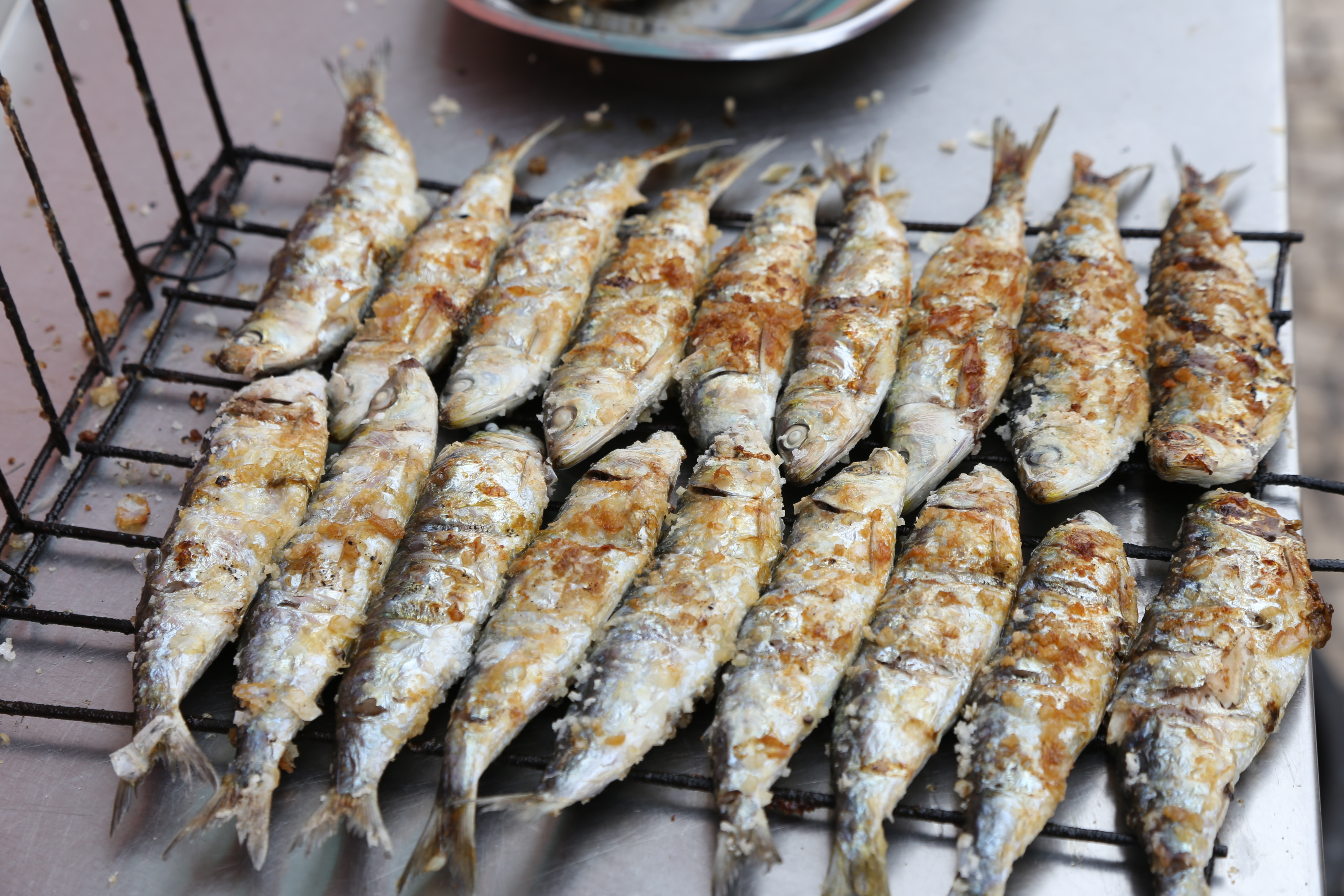Two even rows of 18 grilled fish in total rest on a wire rack.
