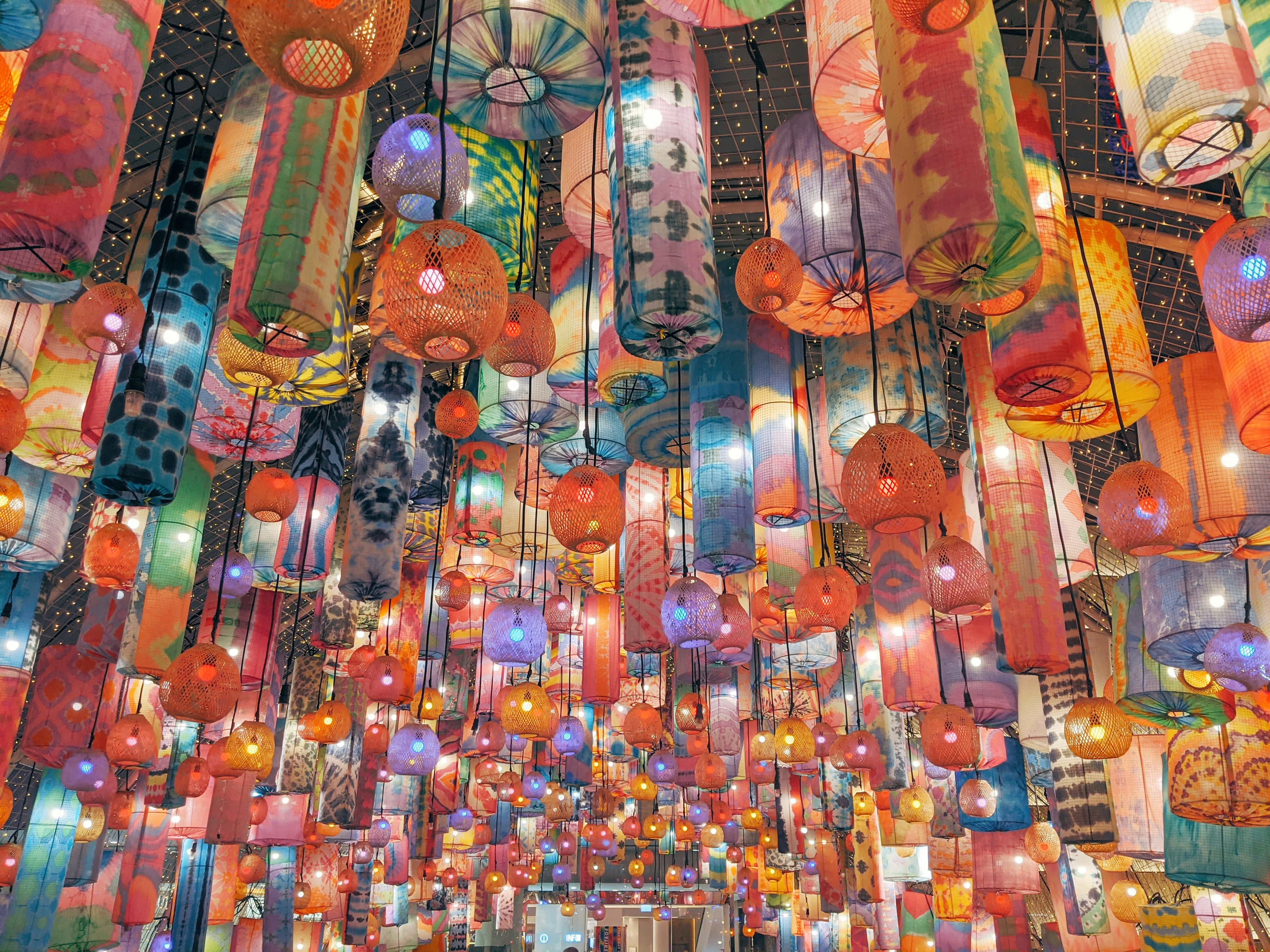 Colorful lanterns hang from the ceiling at a vibrant night market in Bangkok, Thailand.
