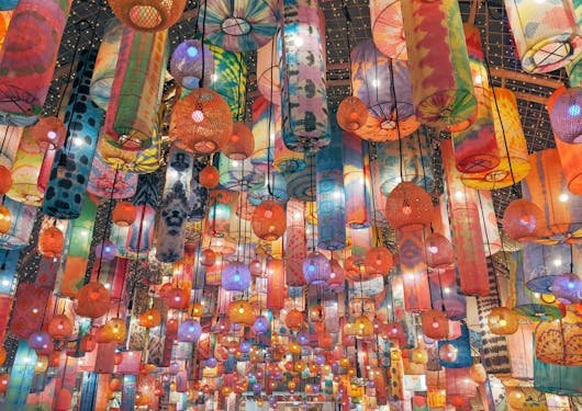 Colorful lanterns hang from the ceiling at a vibrant night market in Bangkok, Thailand.