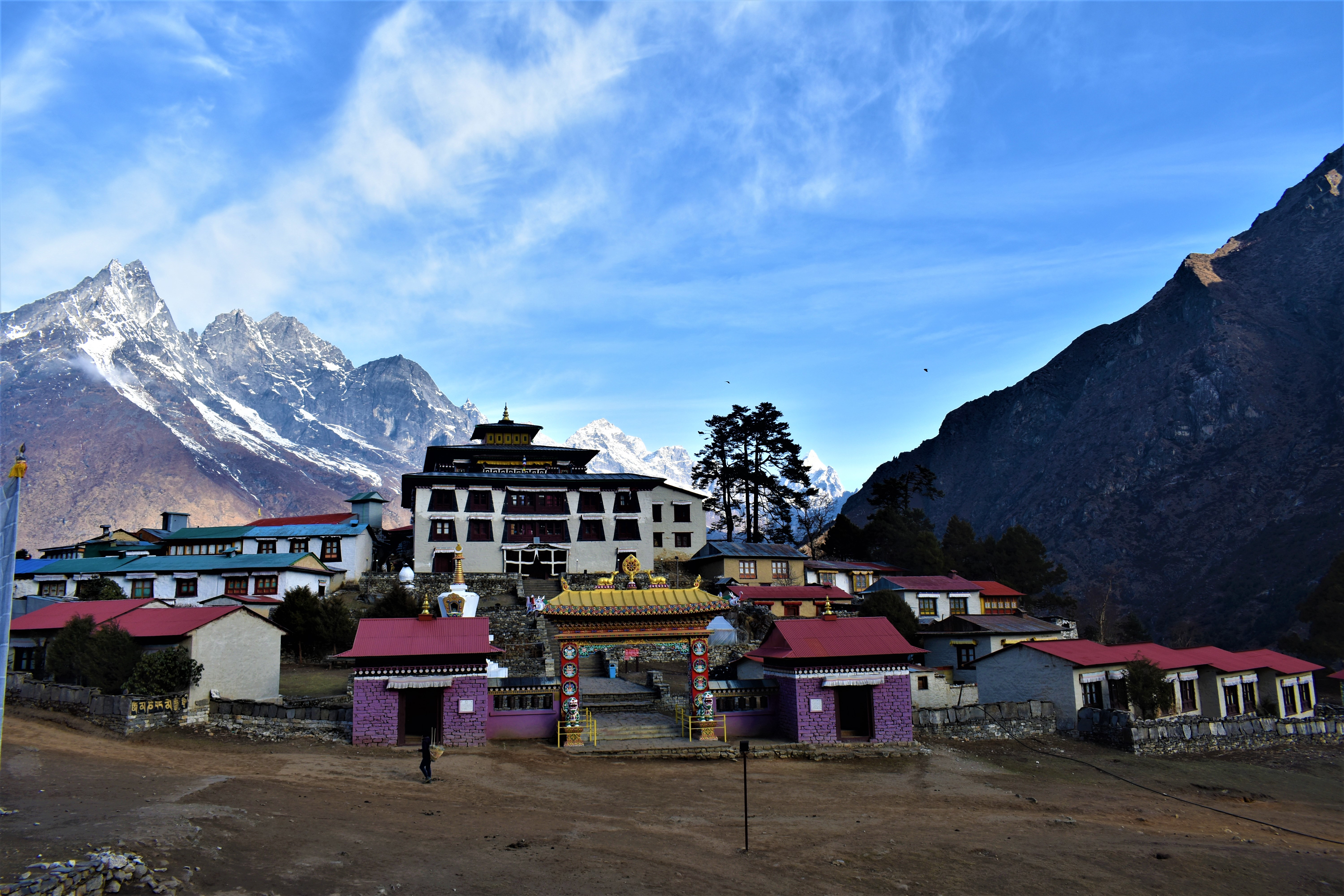 Colorful houses are shown at the base of mountains in front of Tengboche Monastery on the Everest Base Camp Trek.