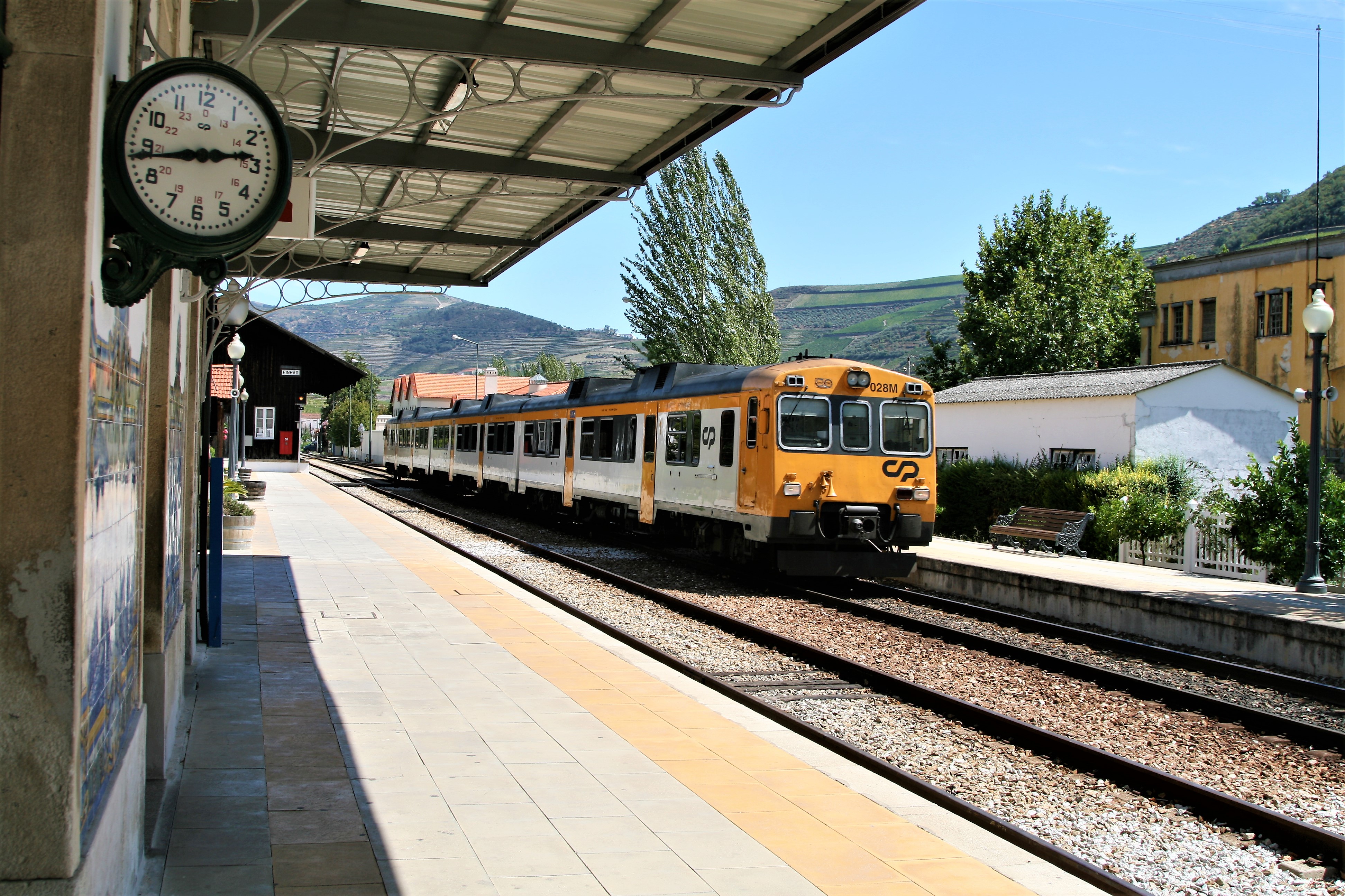 An orange and white train pulls into a station in Portugal's Douro Valley.