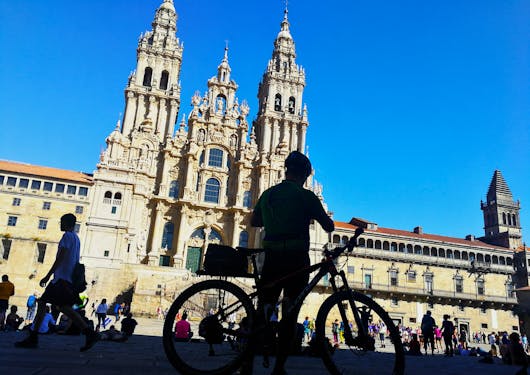 A biker in the shadows stands in front of the majestic Cathedral de Santiago in Spain.