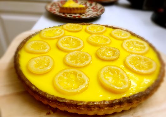 A lemon tart with bright yellow custard and slices of lemon atop it on a gourmet walking tour of the southern French alps. Responsible package trips in France.