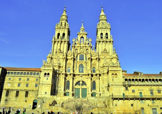 The Cathedral in Santiago, Spain, is shown in full sunlight against a blue sky.