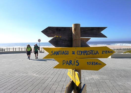 Yellow signs indicated the direction and distance to Santiago de Compostela and Paris alongside a beach in Portugal.