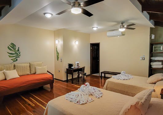 The inside of an accommodation in Sarapiqui is shown in Costa Rica, with two beds and a couch area.