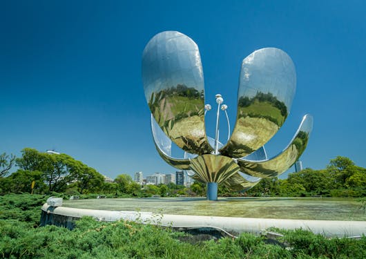 An eye-catching, flower-shaped sculpture reflects the blue sky and green trees in Buenos Aires.