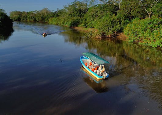A covered boat carries a small group of travelers through the waterways of the Cano Negro wetlands in Costa Rica.