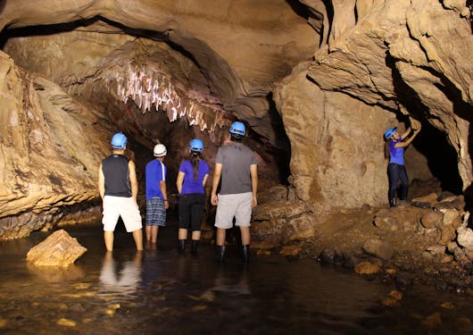A group of 5 adults in hard hats stand in the caves near Arenal, getting ready to explore further.
