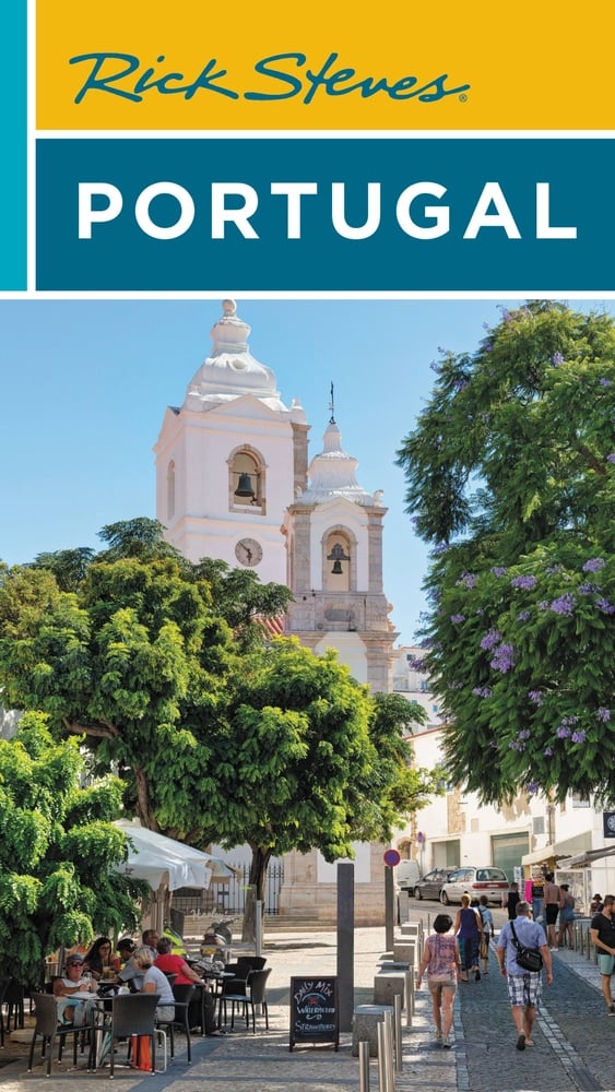 The cover image is shown of Rick Steves' book about Portugal, with a bright sunny image showing trees and a white church.