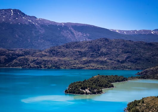 An alpine lake is shown in the wild wilderness of Chilean Patagonia during a responsible supported trek along the El Gaucho Way.