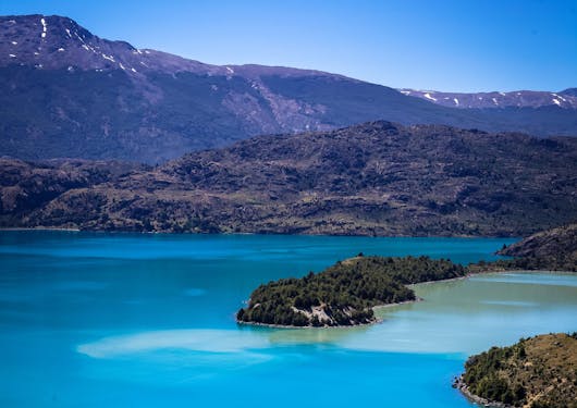 An alpine lake is shown in the wild wilderness of Chilean Patagonia during a responsible supported trek along the El Gaucho Way.