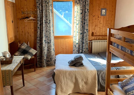 A bedroom is shown in the alpine guesthouse  in the southern French Alps where hikers can stay on a sustainable self-guided walking holiday of the area.