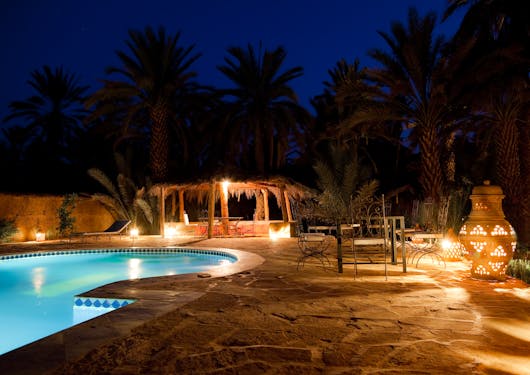 A pool's hotel is shown at night-time in Morocco, an example of where guests might stay on the Morocco Treasures tour.