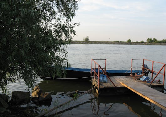 A small motorized boat is shown anchored to a dock on Romania's Danube Delta River.