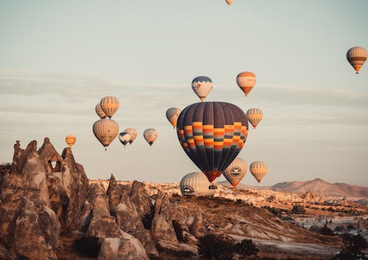 Hot air ballons are seen relatively close up, some just above the ground, in Cappadocia, Turkey.