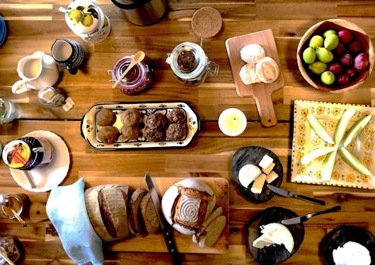 A healthy brunch display of fruit, breads, fruit, and more is laid out artfully across a table.