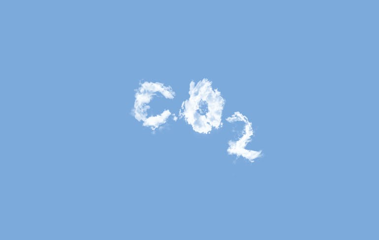 White puffy clouds form a C, an O, and a subscript 2 to represent carbon dioxide; they're set against a blue sky. The text is centered in the frame.