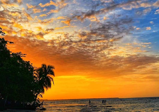 A stunning sunset is shown in Costa Rica, with orange skies fading into blue over a body of water.