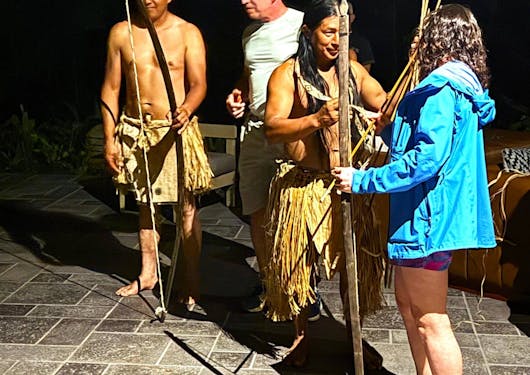 A caucasian adult couple interacts with two indigenous adults in Costa Rica during a cultural workshop.